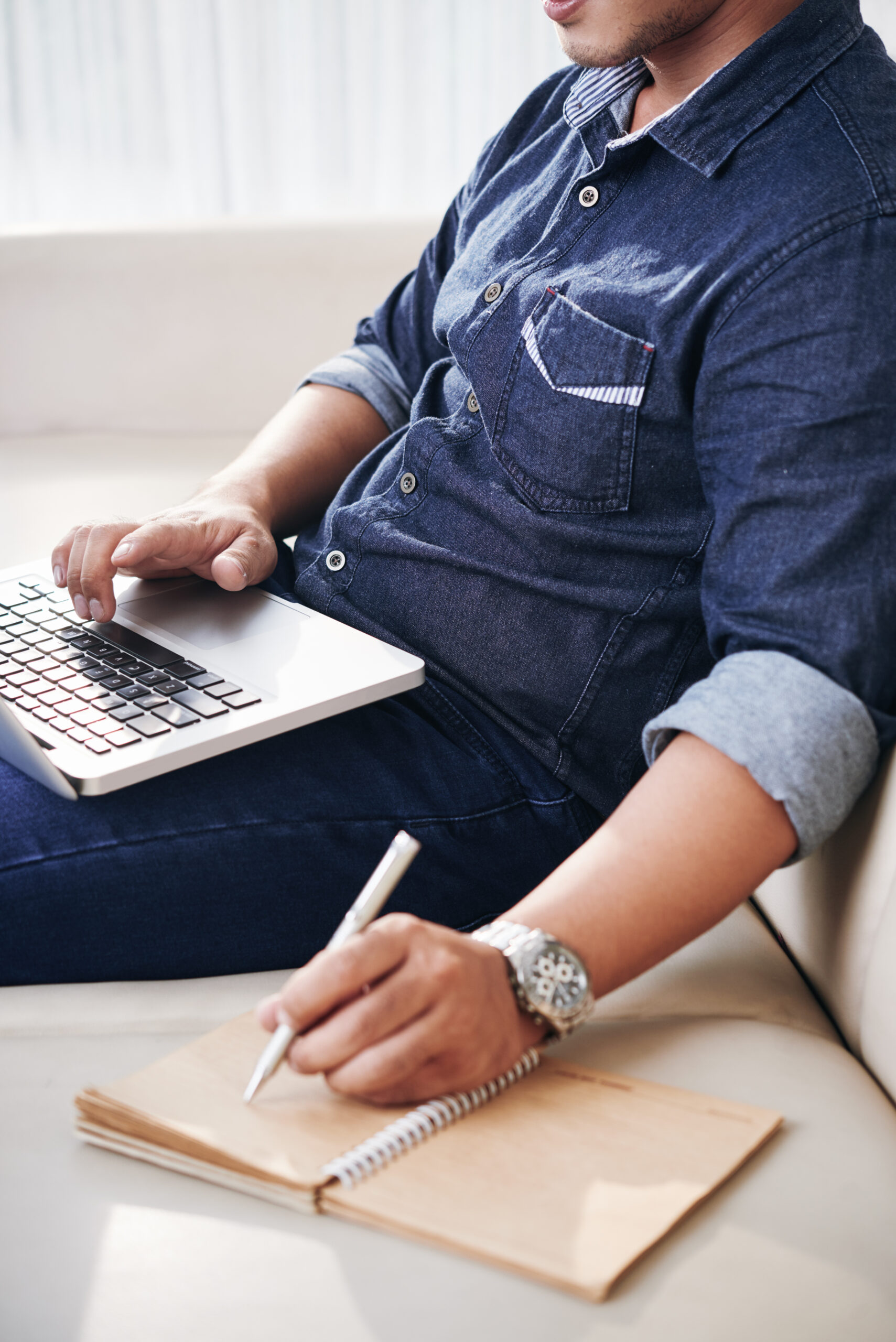 Cropped image of businessman searching for information online and taking notes